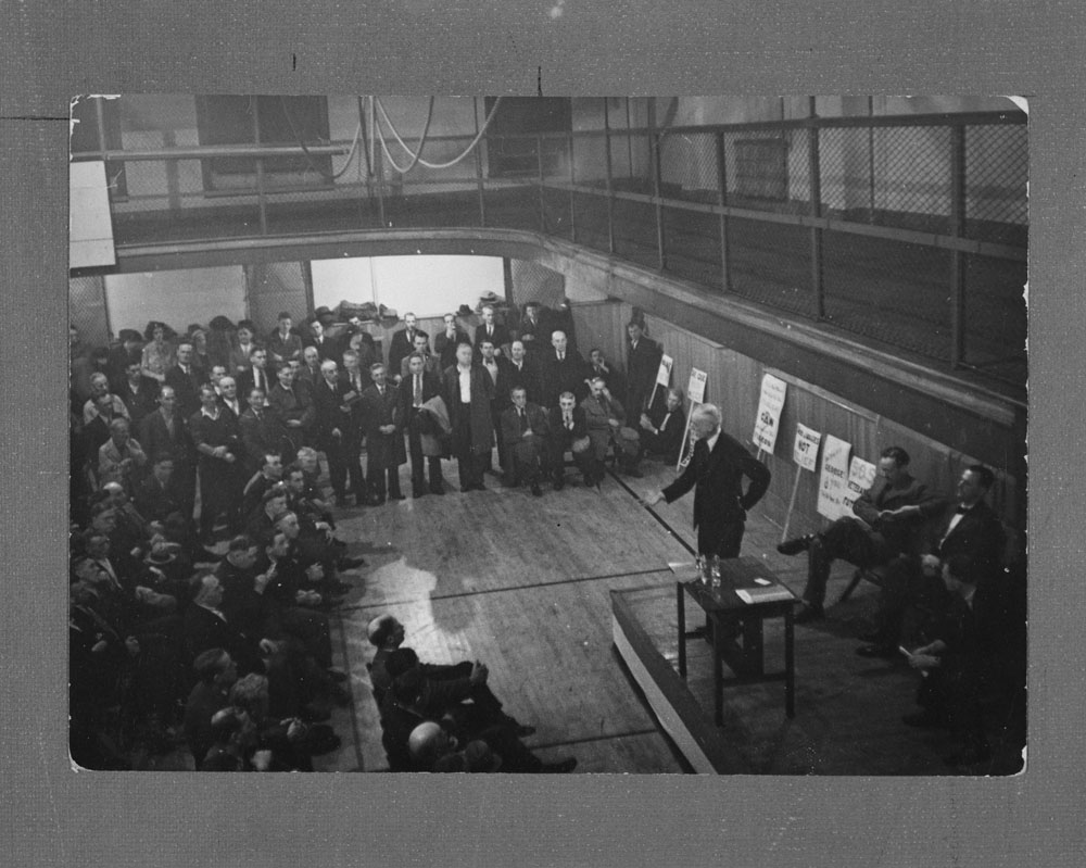 J.S. Woodsworth at work: a black-and-white photograph of the CCF leader speaking before a large audience in a gymnasium